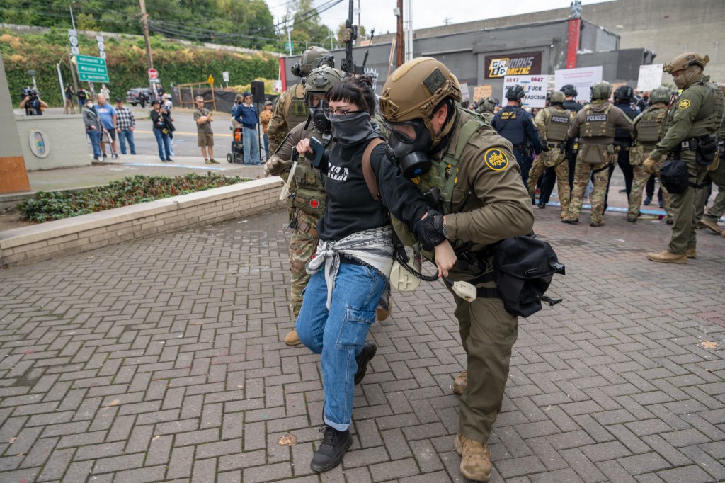 A U.S. Border Patrol agent (right) and an ICE officer detain a protester outside the ICE facility on October 4, 2025 in Portland, Oregon.